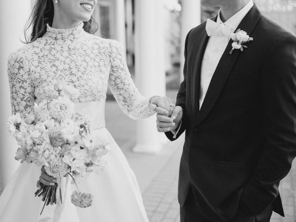 black and with of bride and groom holding hands on wedding day