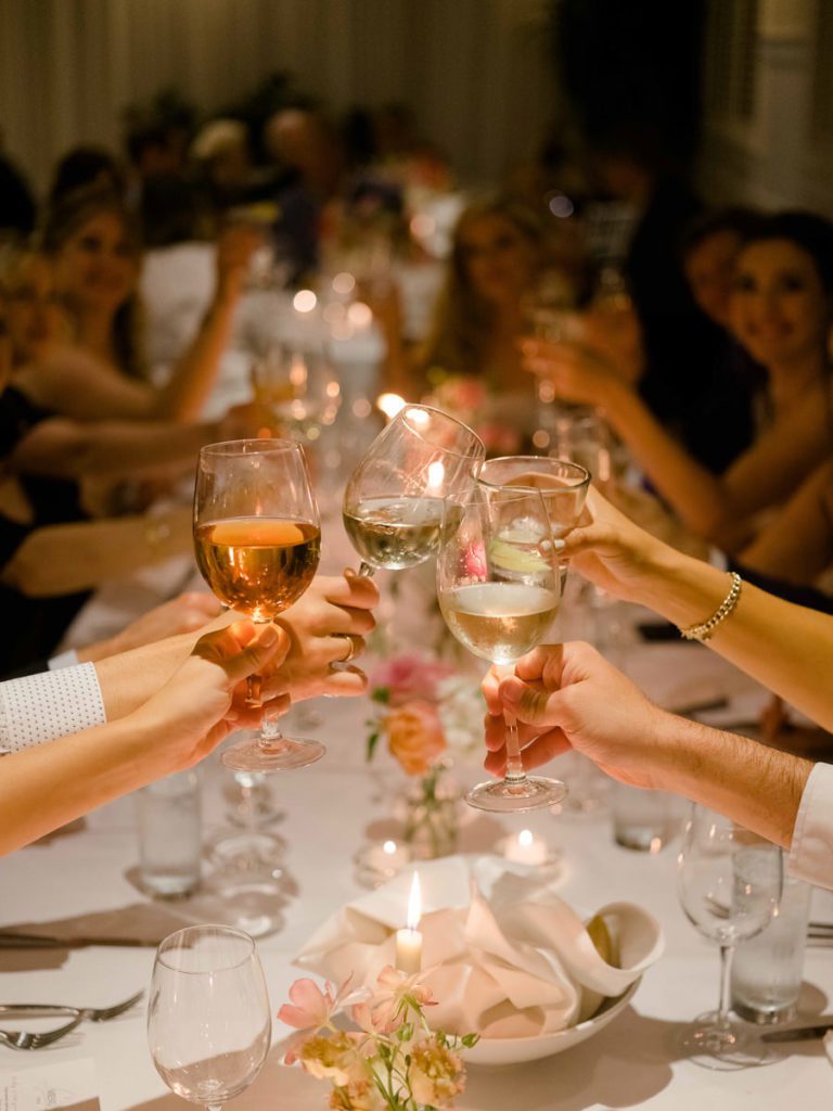A toast with wine glasses at wedding reception dinner