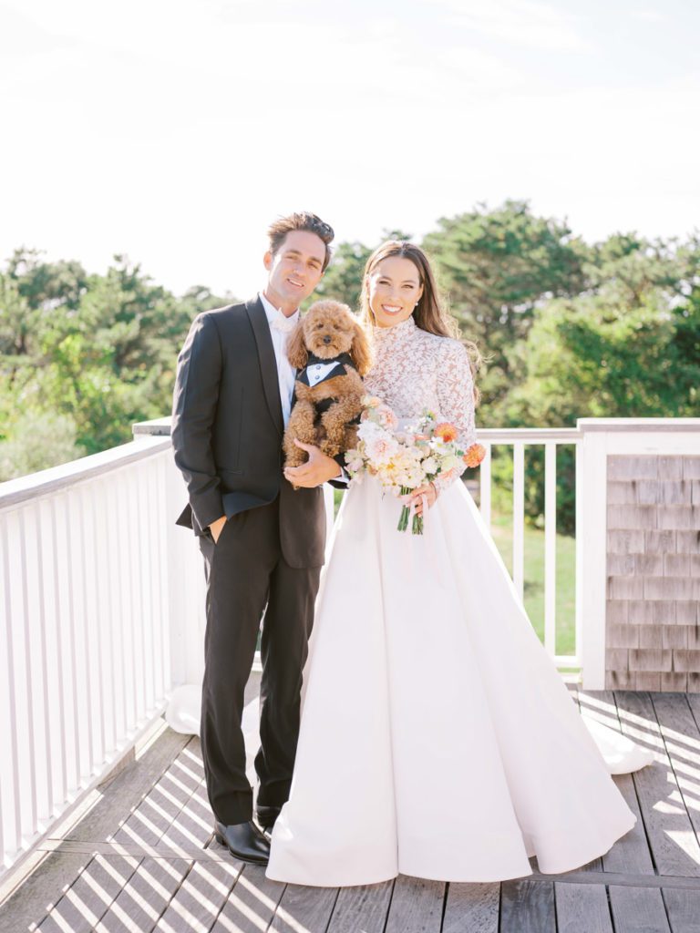 bride and groom with their dog in a tuxedo at wedding