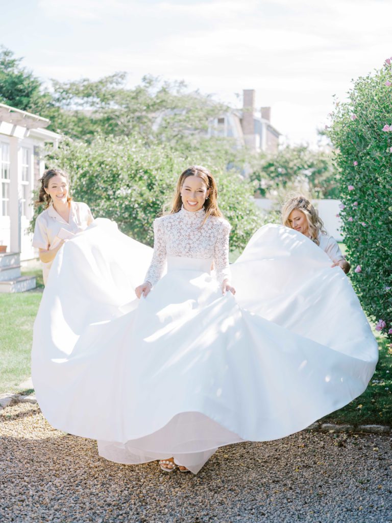 Bride heading to ceremony with her bridesmaids helping hold her gown