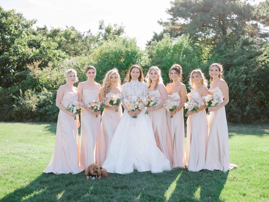 Bride with bridesmaids in champagne dresses with puppy in tuxedo