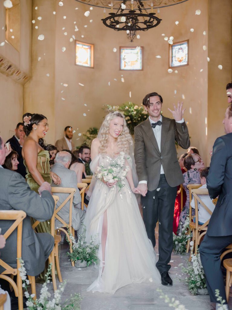 Allegretto Vineyard Resort | bride and groom smiling and exiting their ceremony with a confetti throw and groom shows off his wedding ring