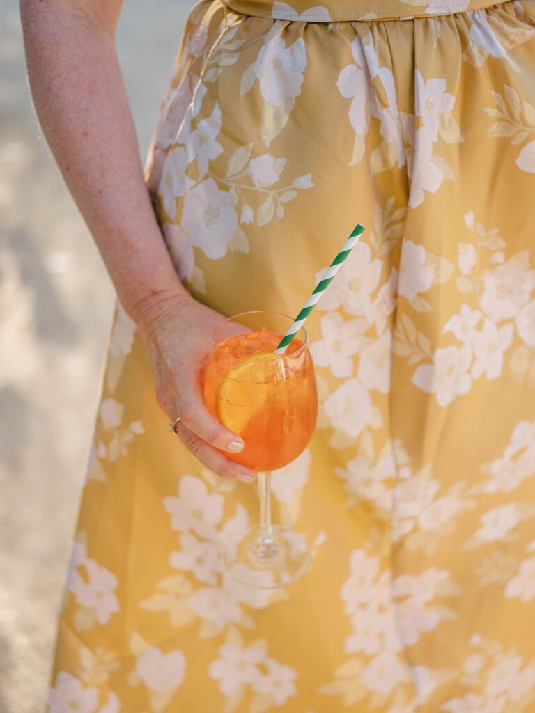 women in yellow dress holding aperol spritz at wedding reception